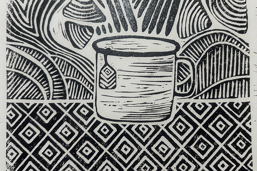 lino cut black and white print of a mug with a tea bag hanging out of it