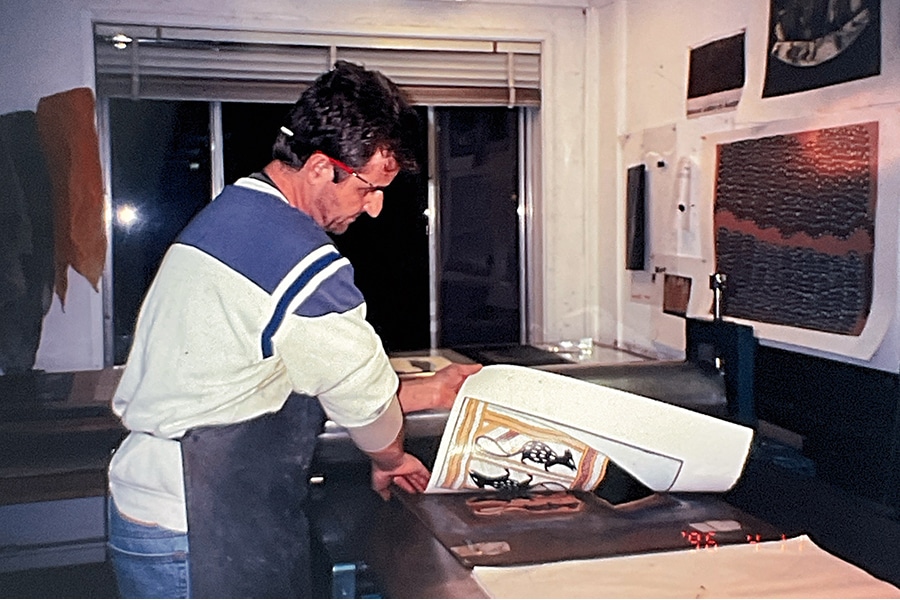 Basil Hall in Studio One, printing Naminapu Maymuru White's lino triptych Nyapilingu (1995). Image courtesy of the artist.