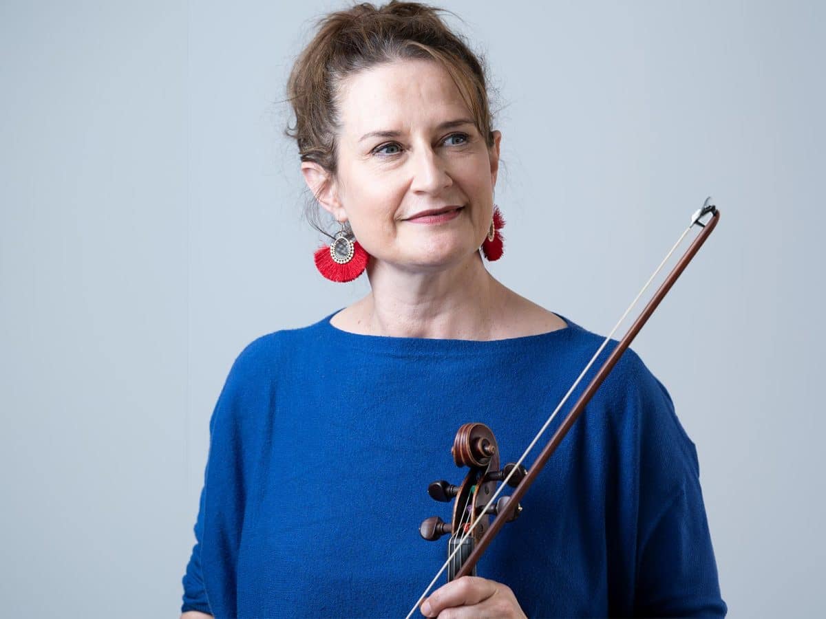 Woman with beautiful red earrings wearing blue and holding a violin