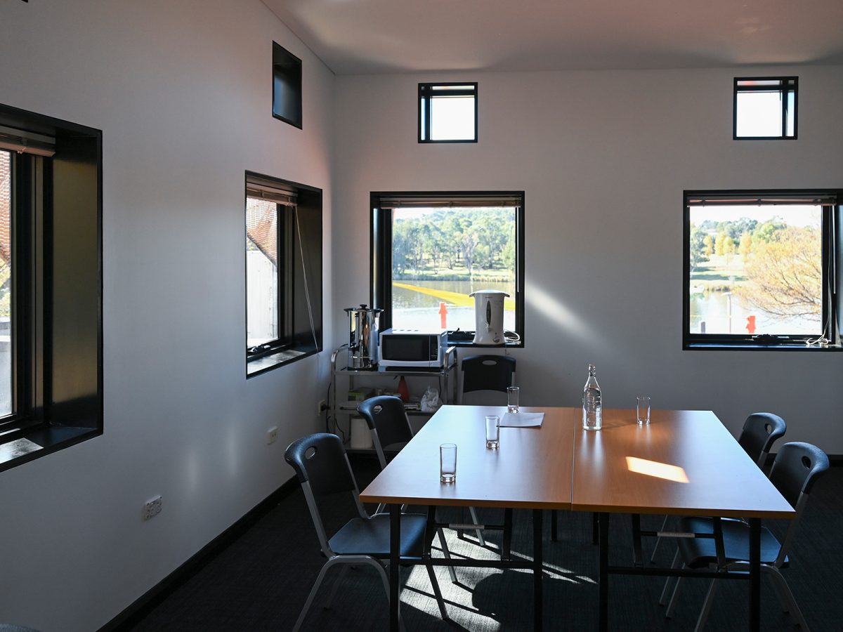 A table and chairs with glasses of water sit in a room that looks out over a lake