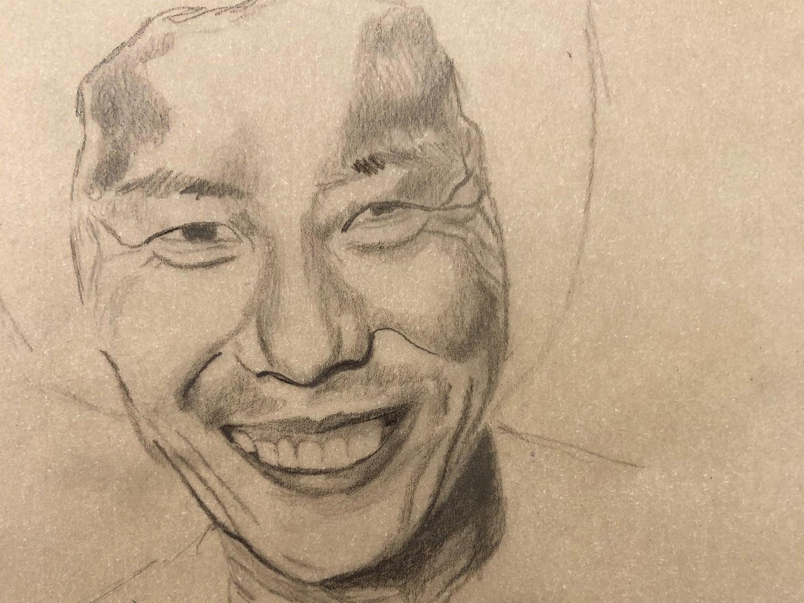 a charcoal drawing on brown paper of a smiling face