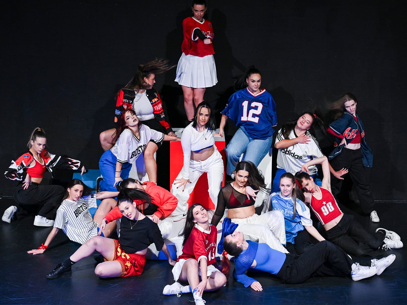 a group of women in white, red and blue pose on stage