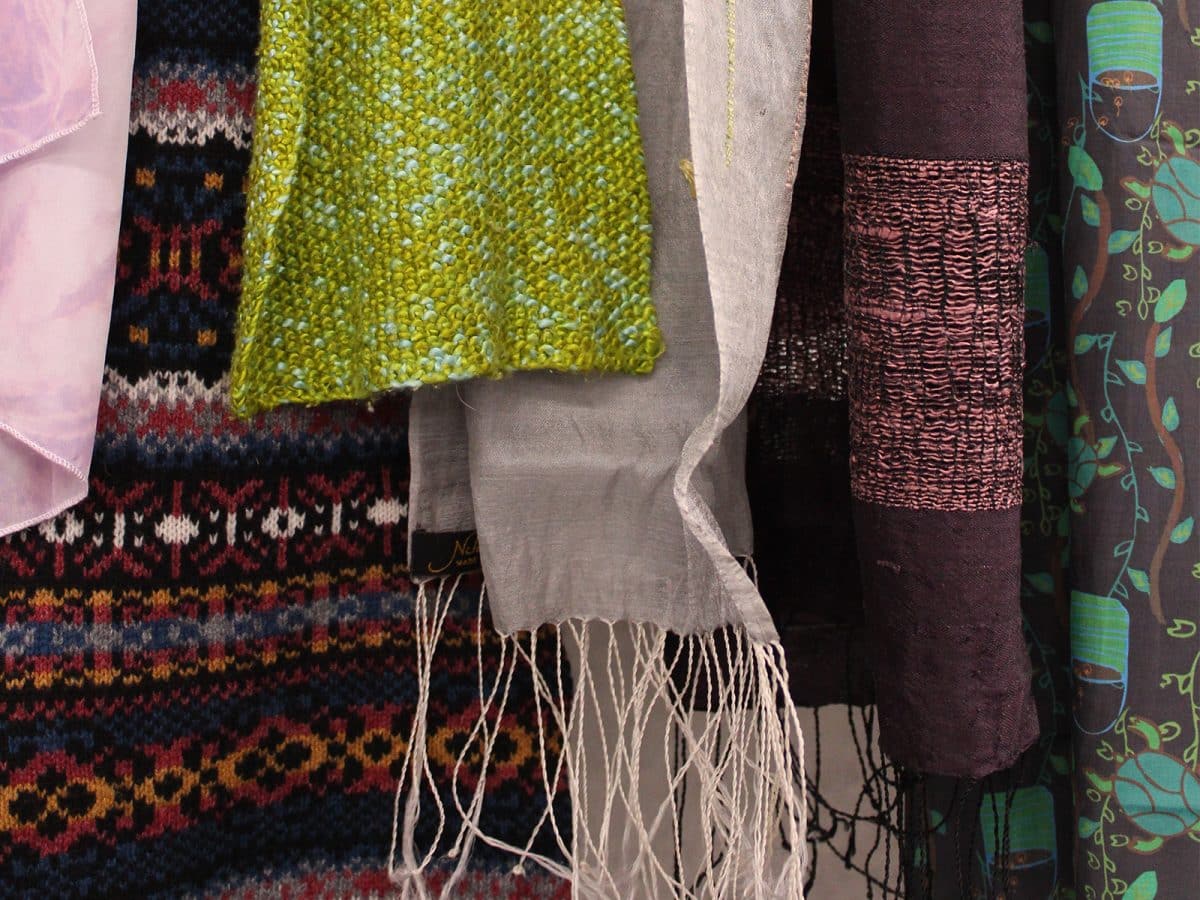 A collection of scarfs hanging in a range of colours and weaves