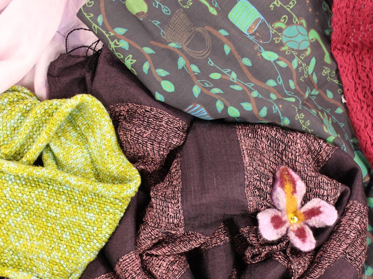 A bundle of green, purple and pink scarfs of different textures and prints.