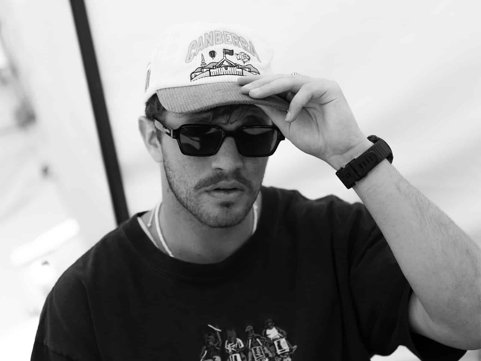 A black and white image with a man in a cap and sunglasses