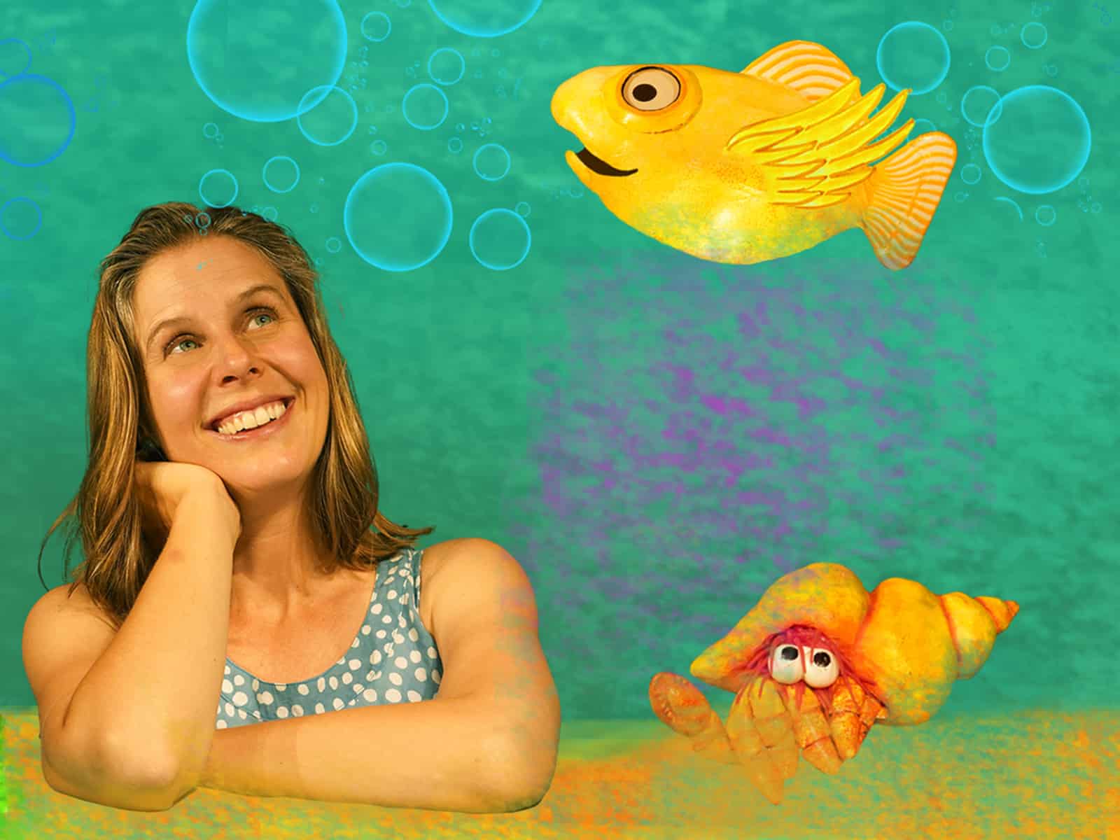 A blond woman leans on a beach. A hermit crab sits next to her and a yellow fish swims above her.