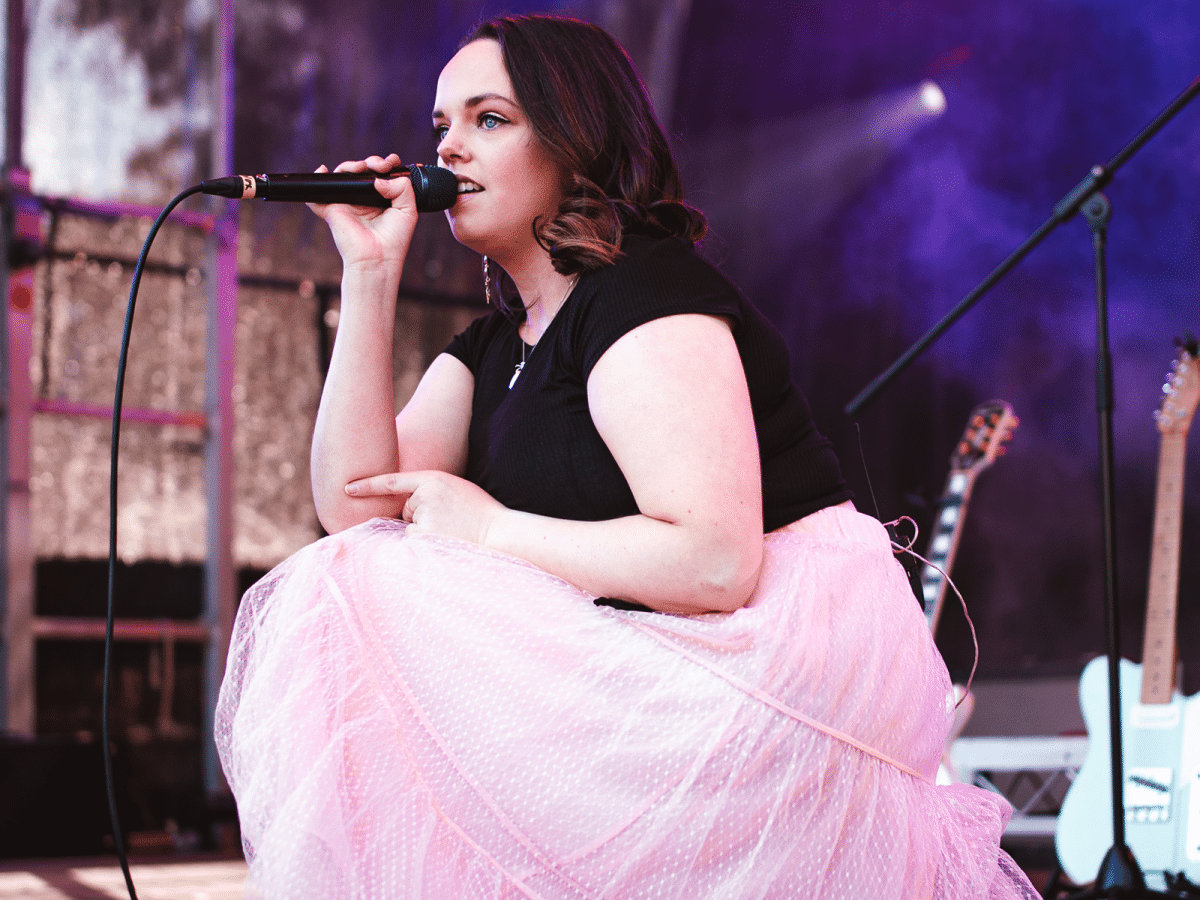 Woman in pink dress holding a microphone on a stage